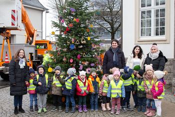 Kinder und Erzieherinnen der städtischen Kita Gartenstraße mit Bürgermeister Mario Dahm rund um den festlich geschmückten Weihnachtsbaum